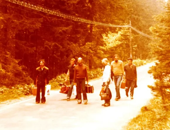 Das vergilbte Foto zeigt Männer, die auf einer Straße Waldweg gehen.