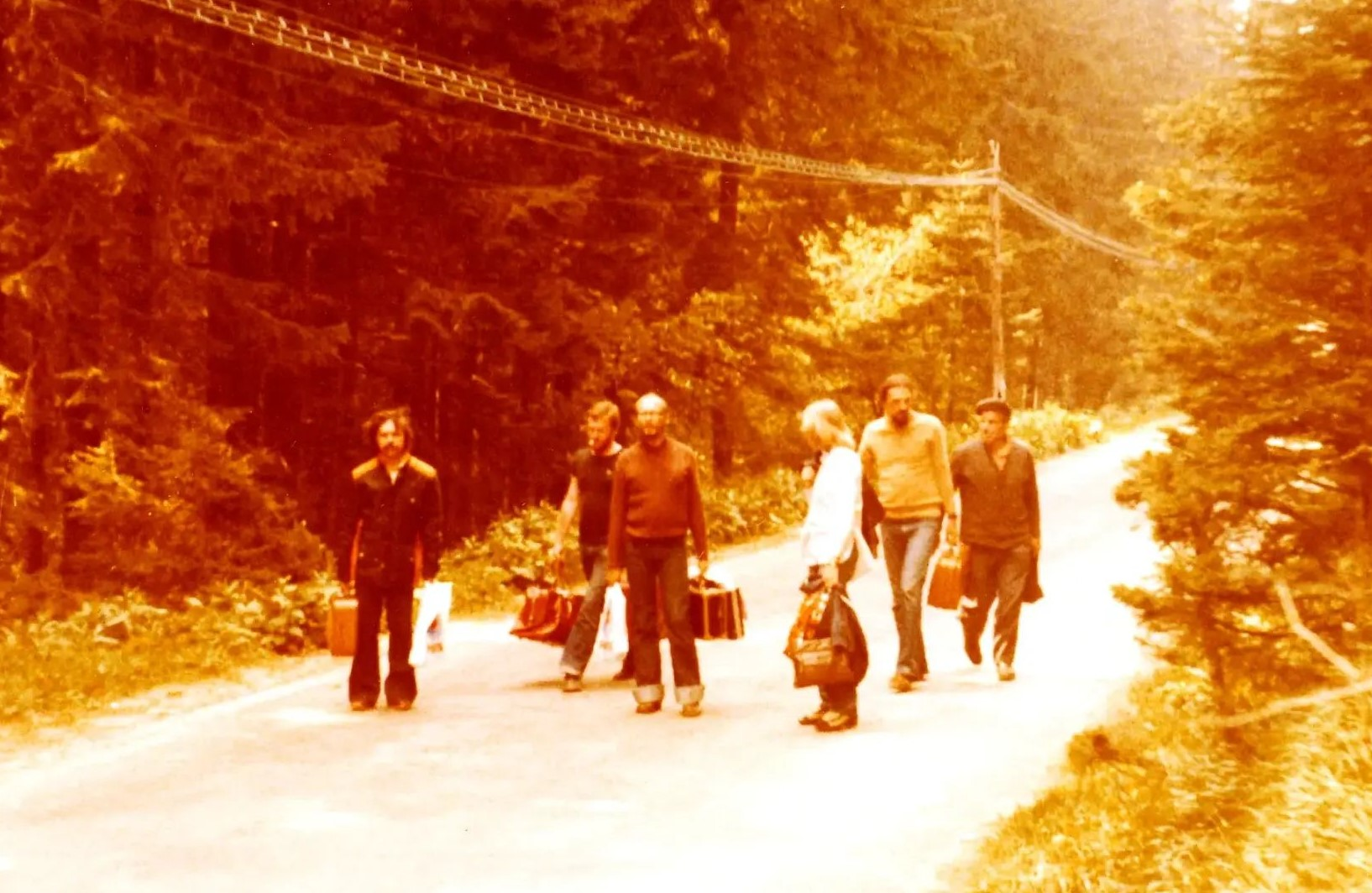 The yellowed photo shows men walking on a forest path.