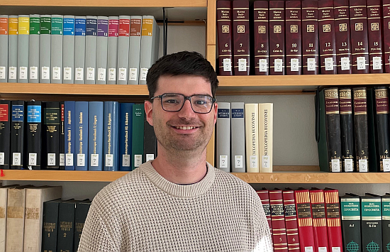 The picture shows Lennart Gröger in front of a bookshelf.