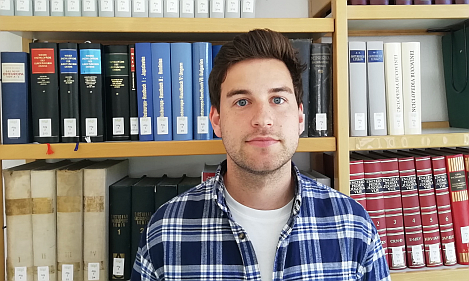 Das Foto zeigt Patrick Schmitt vor einem Bücherregal.