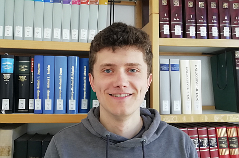 Das Foto zeigt Andreas Sienz vor einem Bücherregal